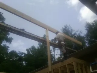 Carpenter setting a ridge beam over a new addition frame — Ice Dam Removal by Roofing Brothers in Saint Martinville