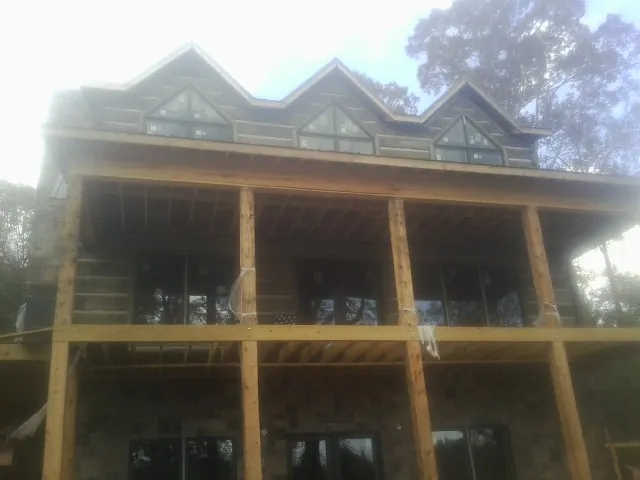 Dormers and porch framing on a large log home under construction — Roof Coating work by our crew in Saint Martinville
