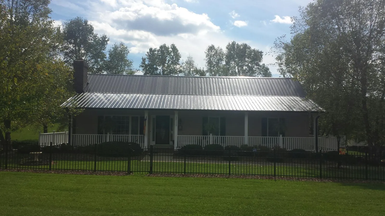 Gray metal roof on a brick ranch with a full width front porch — Gutter Guard Installation work by our crew in Saint Martinville