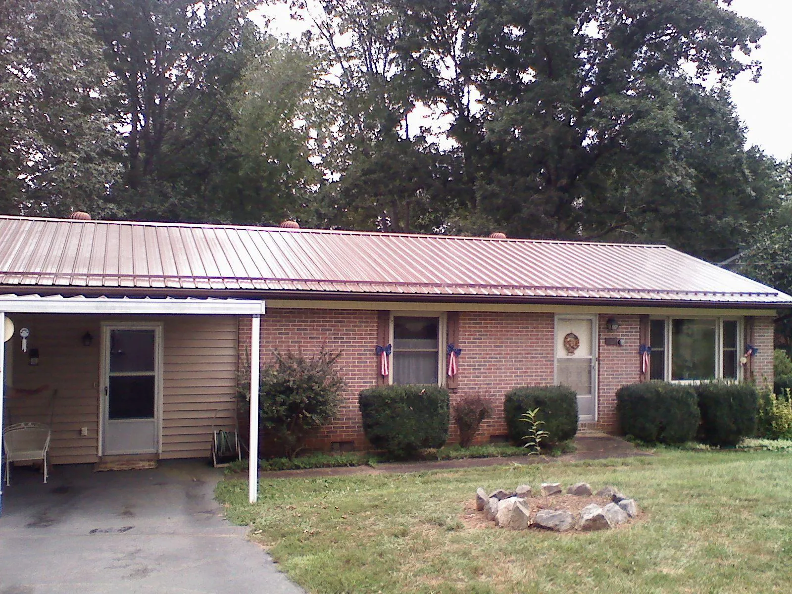 Bronze metal roof and carport on a brick ranch home — Roof Repair work by our crew in Saint Martinville