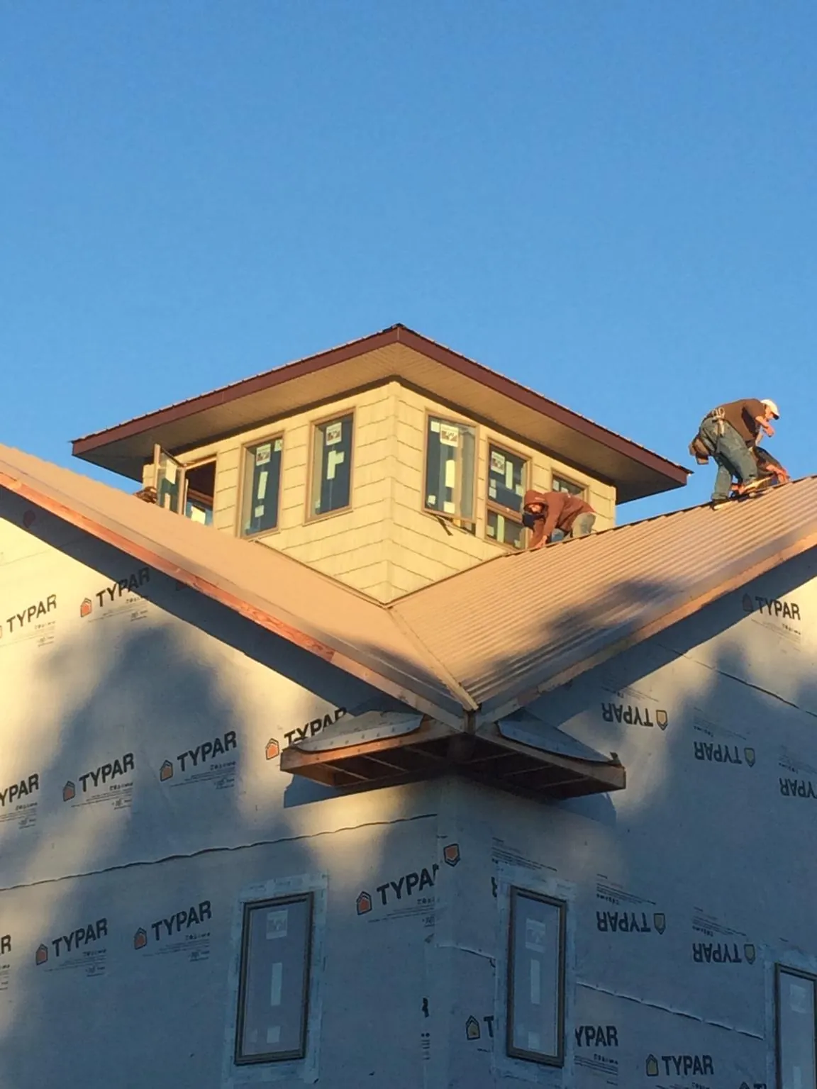 Roofers working around a rooftop cupola on a new metal roof at sunset — Roof Waterproofing in Saint Martinville by Roofing Brothers